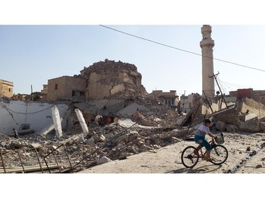 A bicyclist rides by the destroyed old Mosque of The Prophet Jirjis in central Mosul, Iraq, Sunday, July 27, 2014. The revered Muslim shrine was destroyed on Sunday by militants who overran the city in June and imposed their harsh interpretation of Islamic law.