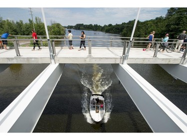 A boat passes under the Strandherd-Armstrong Bridge after its grand opening in Ottawa on Saturday, July 12, 2014. The bridge connects the communities of Barrhaven and Riverside South over the Rideau River.