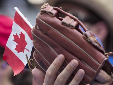 A fan holds a Canadian flag in his baseball glove as the Toronto crowd celebrates Canada Day during interleague baseball action between the Toronto Blue Jays and Milwaukee Brewers in Toronto on Tuesday July 1 , 2014.