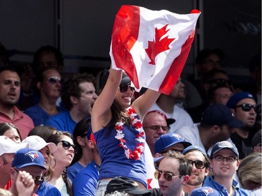 A fan waves a Canadian flag as the crowd celebrates Canada Day during interleague baseball action between the Toronto Blue Jays and Milwaukee Brewers in Toronto on Tuesday July 1 , 2014.