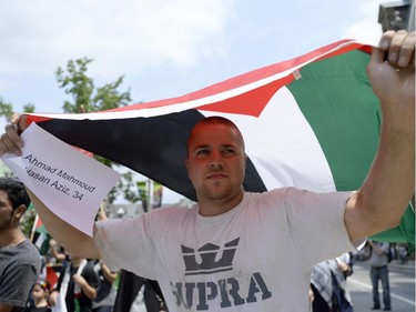 A man holds the Palestinian flag over his head as he protests in front of the Langevin Block in support of Palestinians in Gaza in Ottawa on Tuesday, July 22, 2014.