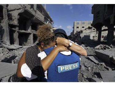 A member of the foreign media, left, cries as she embraces her Palestinian news assistant, right, who burst into tears after discovering his family house was destroyed by Israeli strikes in Beit Hanoun, northern Gaza Strip, Saturday, July 26, 2014. Thousands of Gaza residents who had fled Israel-Hamas fighting streamed back to devastated border areas during a lull Saturday, and were met by large-scale destruction: scores of homes were pulverized, wreckage blocked roads and power cables dangled in the streets.