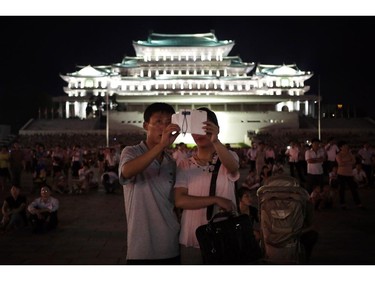 A North Korean couple use their smart phone to photograph fireworks, Sunday, July 27, 2014 in central Pyongyang, North Korea. North Koreans gathered at Kim Il Sung Square to watch a fireworks display as part of celebrations for the 61st anniversary of the armistice that ended the Korean War.(AP Photo/Wong Maye-E)