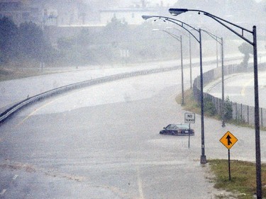 A vehicle sits in the flooded waters of the closed Route 18 on Friday, July 4, 2014, in New Bedford, Mass., after heavy rains from Hurricane Arthur.