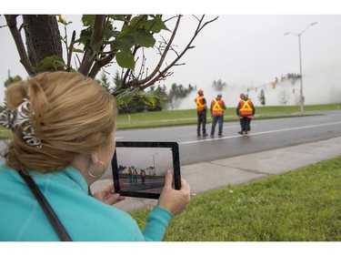 A woman films on her iPad as the Sir John Carling building is demolished in Ottawa on Sunday, July 13, 2014. The former headquarters of Agriculture and Agri-Food Canada at 930 Carling, completed in 1967, is being demolished at a cost of $4.8 million.