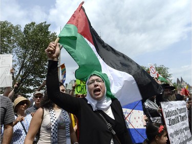 A woman participating in a rally in support of Palestinians in Gaza reacts to pro-Israel protesters counter-protesting in front of the Langevin Block in Ottawa on Tuesday, July 22, 2014.
