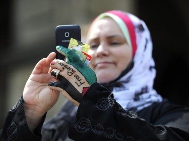 A woman with "Free Palestine" henna on her hand takes a photograph with her smartphone during protests in front of the Langevin Block in support of Palestinians in Gaza in Ottawa on Tuesday, July 22, 2014.