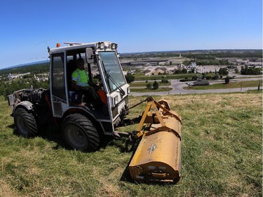A worker cuts the grass at the top of "Carp Mountain" at Carp Road landfill.