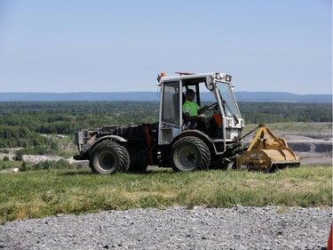 A worker cuts the grass at the top of "Carp Mountain" at Carp Road landfill.