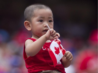 A young fan holds a flag as the Toronto crowd celebrate Canada Day during interleague baseball action between Toronto Blue Jays and Milwaukee Brewers in Toronto on Tuesday July 1 , 2014.