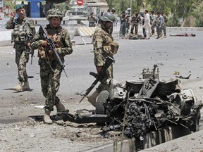 Afghan security forces inspect the site of a suicide attack in the city of Kandahar south of Kabul, Afghanistan, Wednesday, July 9, 2014.