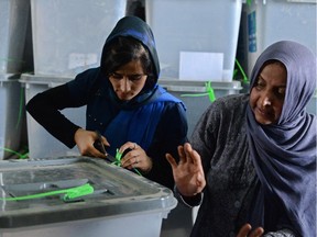 An Afghan election commission worker cuts open the seals to a box containing ballot papers for an audit of the presidential run-off votes at a counting centre in Kabul on July 17, 2014. Afghanistan on July 17 began a massive audit of 8.1 million ballots cast in the run-off round of its controversial presidential vote, hours after a brazen Taliban raid on Kabul's airport.