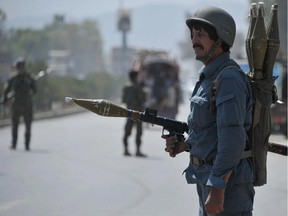 An Afghan policeman armed with a rocket-propelled grenade (RPG) launcher stands guard following a rickshaw bomb explosion in Jalalabad on July 12, 2014. At least two people including a policeman were killed and two civilians wounded when their vehicle was hit by a remote control bomb, provincial spokesman Ahmad Zia Abdulzai said.