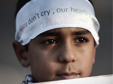 A Bahraini boy wears a headband reading "Gaza don't cry" during a protest against Israel's military operation in the Gaza Strip on July 26, 2014, in the village of Karranah, west of Manama. The placard reads in English: "stop killing Gaza's children". Israel approved a four-hour extension of a temporary truce in Gaza, Israeli television said, after the Palestinian death toll topped 1,000 with the retrieval of more than 130 bodies.