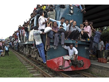 Bangladeshi Muslims sit on to the engine of an overcrowded train as they head to their homes ahead of Eid al-Fitr at a railway station in Dhaka, Bangladesh, Sunday, July 27, 2014. Eid al-Fitr marks the end of the holy fasting month of Ramadan.