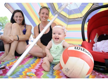 Beatrix Whiteside, 7 months, plays with a volleyball at the HOPE Volleyball Summerfest at Mooney's Bay Beach in Ottawa as mom Shannon, centre, and her friend Shannon Poirier look on on Saturday, July 12, 2014.