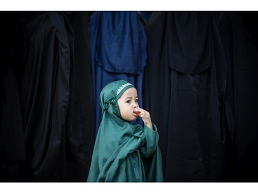 GOWA, SULAWESI, INDONESIA - JULY 27:   A girl from Islamic commune An-Nadzir  drinks jelly during Eid Al Fitr mass prayer at Mawang Lake on July 27, 2014 in Gowa, South Sulawesi, Indonesia. Exclusive Islamic community An-Nadzir has 5,000-10,000 followers across Indonesia, one of world's largest Muslim nation. Their beliefs are the same as mainstream Muslims, but there are some differences in prayer timings and fast breaking methods. They pray before breaking their fast unlike other Muslims who do the opposite. The men dressing in dark robes and colour their hair while women are draped in head-to-toe burqas. In the remote area in Gowa district, the community live a basic life of farming and fishing, condemn militancy of any kind, and believe in salvation without discrimination and living in peace with others. By carrying out a manual calculation based on ru'yat (lunar sighting) and observations on several signs of nature, the An Nadzir muslim community decided that Eid Al Fitr 1435 H in this year fell on Sunday.