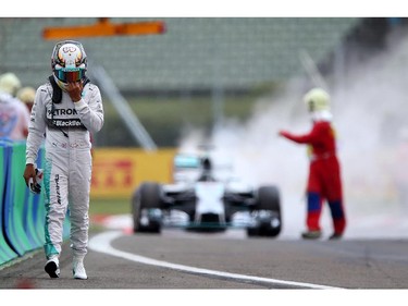 BUDAPEST, HUNGARY - JULY 26:  Lewis Hamilton of Great Britain and Mercedes GP walks away from his car after it caught fire during qualifying ahead of the Hungarian Formula One Grand Prix at Hungaroring on July 26, 2014 in Budapest, Hungary.