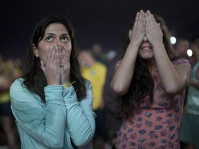 Brazil soccer fans react as they watch their team lose a World Cup semi-final match against Germany, on Copacabana beach in Rio de Janeiro, Brazil, Tuesday, July 8, 2014. Germany poured in the goals Tuesday to hand Brazil its heaviest World Cup loss ever with an astounding 7-1 rout in the semifinals that stunned the host nation.