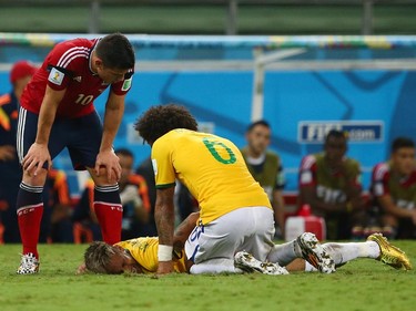 FORTALEZA, BRAZIL - JULY 04:  Neymar of Brazil lies on the field after a challenge as teammate Marcelo and James Rodriguez of Colombia look on during the 2014 FIFA World Cup Brazil Quarter Final match between Brazil and Colombia at Castelao on July 4, 2014 in Fortaleza, Brazil.