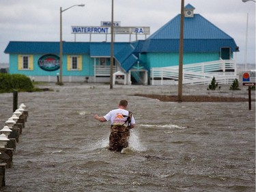 Bryan Wilson, owner of Miller's Waterfront restaurant, braves floodwaters to check the damage to his property as wind from the Hurricane Arthur pushes water to his parking lot in Nags Head, N.C. Friday, July 4, 2014. Arthur struck North Carolina as a Category 2 storm with winds of 100 mph late Thursday, taking about five hours to move across the far eastern part of the state.