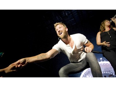 Charles Kelley reaching out to hold the hand of a girl in the front row at the Bell Stage.