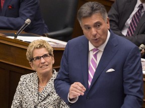 Ontario Premier Kathleen Wynne, left, listens as Finance Minister Charles Sousa delivers the 2014 budget at Queen's Park in Toronto on Monday, July 14, 2014. THE CANADIAN PRESS/Darren Calabrese