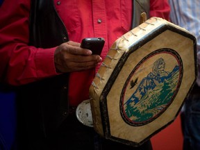 Chief Roger William, of the Xeni Gwet'in First Nation, checks his iPhone while holding a traditional drum during a news conference in Vancouver, B.C., after the Supreme Court of Canada ruled in favour of the Tsilhqot'in First Nation, granting it land title to 438,000-hectares of land on Thursday June 26, 2014.