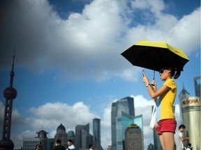 A woman takes a 'selfie' at the Bund promenade before the skyline of the Lujiazui Financial District in Shanghai on July 23, 2014. Summer marks the peak tourist season in Shanghai with tens of thousands of domestic tourists visiting.