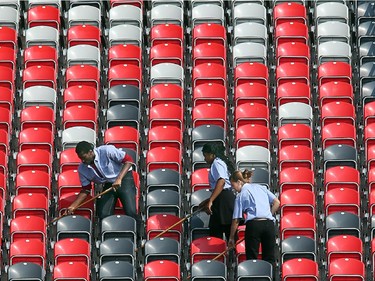 Cleaners sweep out the rows of seats in the north stands. On the inaugural opening day of TD Place July 18, 2014.