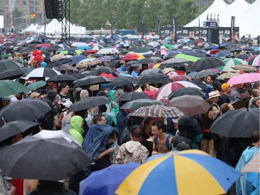 Crowd waits patiently under umbrellas for Styx on Tuesday, July 8, 2014.