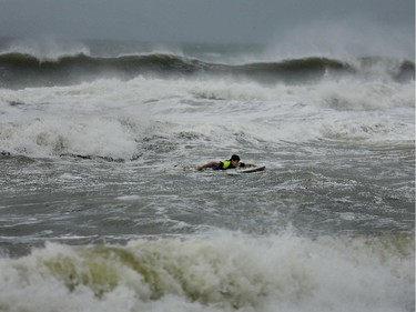 Danny Yates, a William and Mary law student, paddles out through waves created by the remnants a storm, Friday, July 4, 2014, in Sandbridge, Va. The storm was expected to bring a lousy July Fourth beach day with it as it moved offshore of the northeast coast.