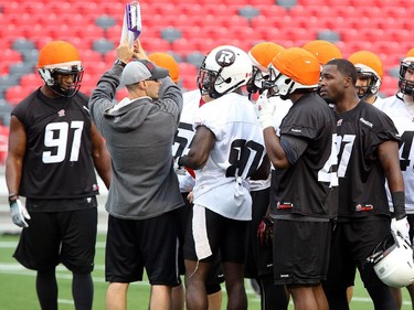 Defensive assistant Derek Oswalt, left, goes over the playbook with some players before a drill as the Ottawa Redblacks have their first practice at home since losing their opening season game against Winnipeg.