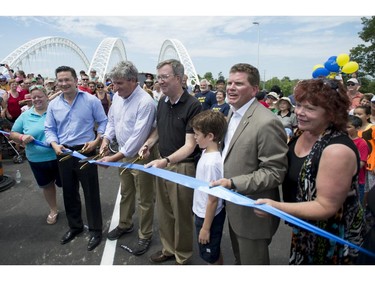 Dignitaries including Councillor Maria McRae, left, MP for Nepean Carleton Pierre Pollievre, MPP for Ottawa South John Fraser, Mayor Jim Watson, Councillor Steve Desroches and his son Jack, 9, and Councillor Jann Harder   cut the ribbon at the grand opening of the Strandherd-Armstrong Bridge in Ottawa on Saturday, July 12, 2014. The bridge connects the communities of Barrhaven and Riverside South over the Rideau River.