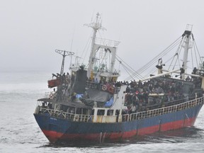 Hundreds of passengers crowd the deck of Motor Vessel (MV) Sun Sea after spotting the arrival of HMCS Winnipeg.