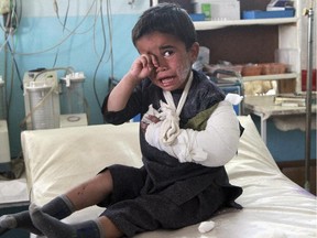 In this May 12, 2014 file photo, an injured boy sits on a bed following an attack, at a hospital in Ghazni city, Afghanistan.