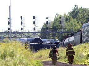 Fire fighters walk near the derailed train near Brockville, Ont., on Thursday July 10, 2014, after 26 cars jumped the tracks.