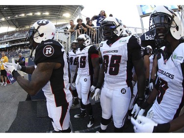 Former Winnipeg Blue Bombers and now Ottawa Redblacks Jovon Johnson, left, leads his team onto the field for their first ever CFL game at Investors Group Field against the Winnipeg Blue Bombers Thursday night.