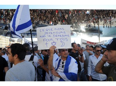 A man wrapped in an Israeli flag holds a placard reading "What we defend, We defend for all" as he takes part in a demonstration supporting Israel on July 27, 2014 in Marseille, southeastern France. The Islamist Hamas movement continued firing rockets at Israel on July 27, despite claims it had accepted a UN request for a 24-hour extension of a humanitarian truce in war-torn Gaza, and renewed Israeli raids on Gaza, which followed a 24-hour lull, killed nine Palestinians, raising the overall toll from the 20-day operation to more than 1,050.