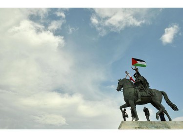 A protestor holds a Palestinian flag after climbing on a monument during a demonstration in Lyon, central eastern France, on July 26, 2014 against Israel's military campaign in Gaza and show their support for the Palestinian people.
