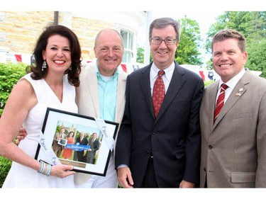 From left, Vicki Heyman and U.S. Ambassador Bruce Heyman with a gift from Mayor Jim Watson and Deputy Mayor Steve Desroches at the embassy's annual Independence Day party held Friday, July 4, 2014, in Rockcliffe.