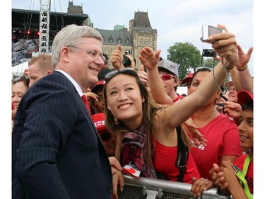 Prime Minister Stephen Harper smiles as has his picture taken with a Canada Day celebrant on Parliament Hill in Ottawa, Tuesday July 1, 2014.