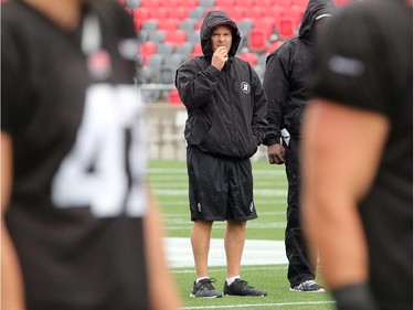 Head coach Rick Campbell stands at centre field in a downpour, keeping an eye on his players as the Ottawa Redblacks practice through a downpour Tuesday morning at TD Place Stadium at Lansdowne Park.