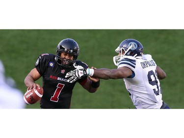 Henry Burris of the Ottawa Redblacks is tackled by Tristan Okpalaugo of the Toronto Argonauts at TD Place in Ottawa during the franchise home opener of the Redblacks on Friday, July 18, 2014.
