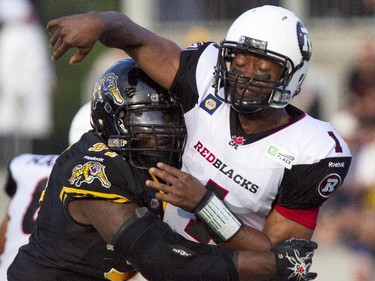Ottawa RedBlacks quarterback Henry Burris, right, is hit by Hamilton Tiger-Cats tackle Ted Laurent as he makes a pass in first quarter CFL action in Hamilton, Ont., Saturday, July 26, 2014.