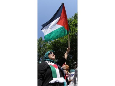 Hundreds of people rally, including this woman, in support of Palestine at the Human Rights Memorial in Ottawa, Saturday, July 12, 2014. Many brought banners and flags, and chanted, and later, they marched toward another rally in front of the US embassy on Sussex Dr.