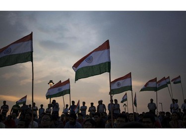 Indians hold their national flags and watch a musical tribute to war heroes on the 15th anniversary of India's victory in the Kargil War, in New Delhi, India, Saturday, July 26, 2014. The 1999 conflict with Pakistan raged for three months across the disputed Kashmir region and nearly brought the nuclear neighbors to a war.