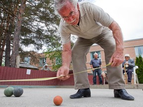 Joe Pagliaro measures for the winning ball as some of the men of Villa Marconi who play bocce ball are featured in a Life centrepiece story about the game played in Ottawa. Photo taken at 13:59 on June 6, 2014.