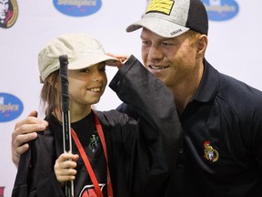 Kiarra Kooyman, 10, adjusts her cap before posing for a photograph with Ottawa Senator Chris Neill.