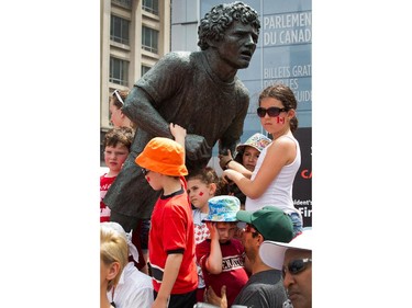 Kids use the Terry Fox statue to get a better look at what's going on as people flock to Parliament Hill and the downtown core to enjoy Canada's 147th birthday.